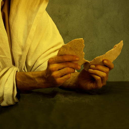 Jesus hands tearing bread for the sacrament.