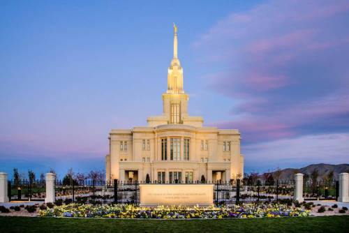 Photo of the Payson Utah Temple behind a yellow and purple flowerbed.