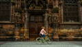 Femme à vélo devant l'entrée d'une cathédrale gothique