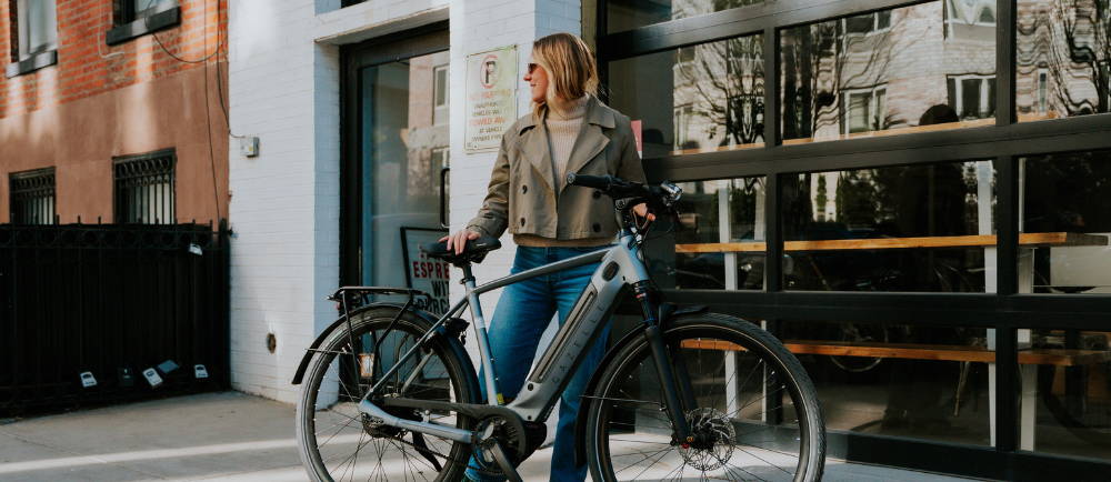 a woman standing next to a Gazelle Ultimate C380+ electric city bike