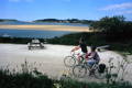 a picture of a couple cycling along the camel trail, looking towards the atlantic ocean and the coast of north cornwall