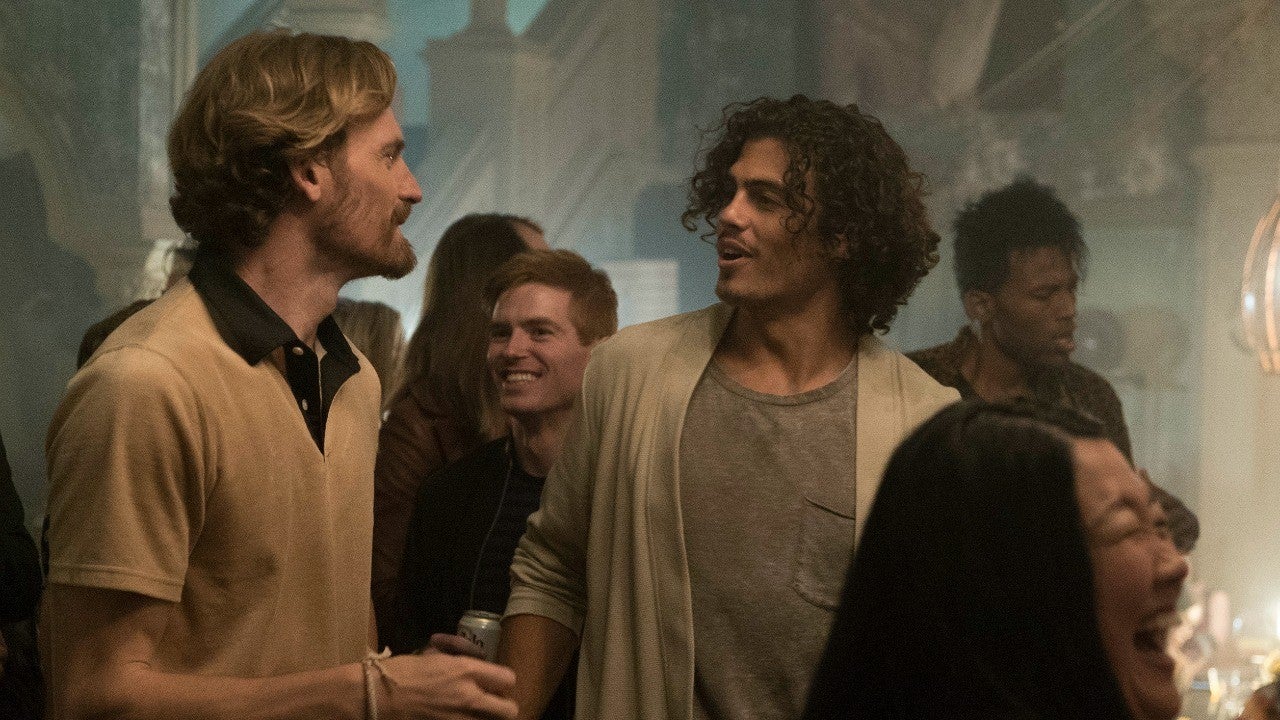 Image of Gael talking to another man while at a house party surrounded by smiling people.