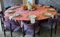 round velvet tablecloth on a big table for 11 people with plates, silverware and placemats, there are also some pumpkins in the center of the table