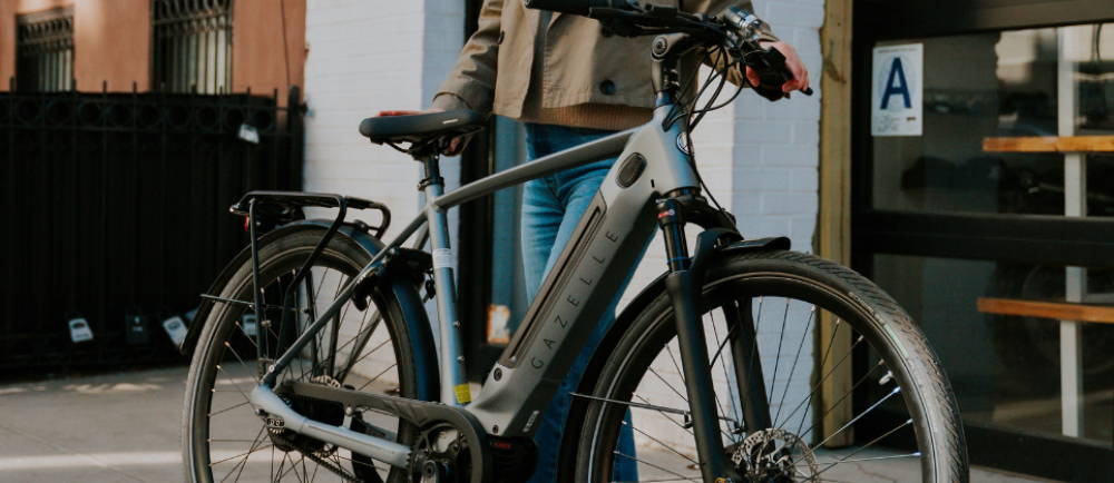 a person standing next to a gazelle electric bike
