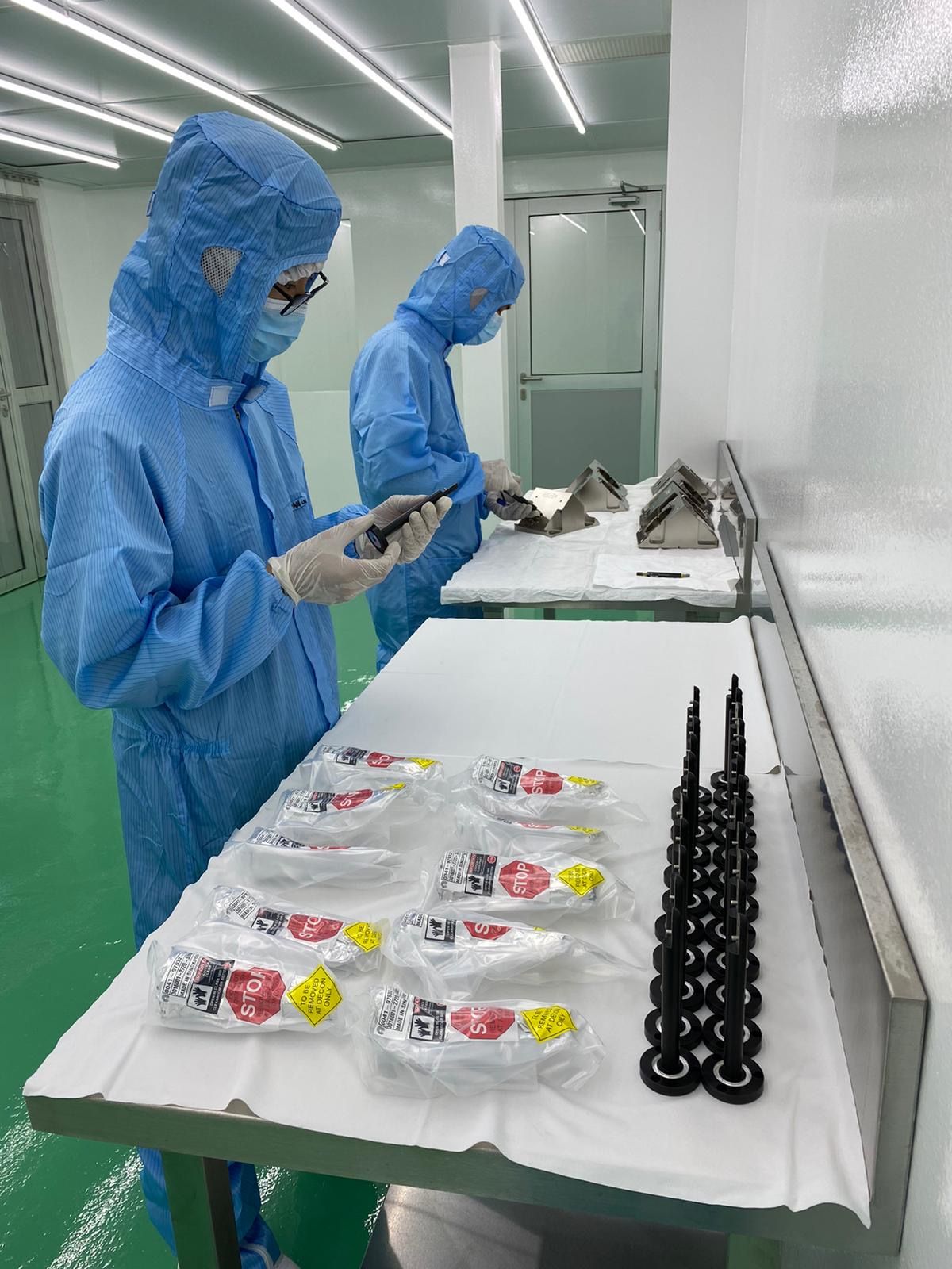 Two staff wearing PPE in a cleanroom performing assembly of a product