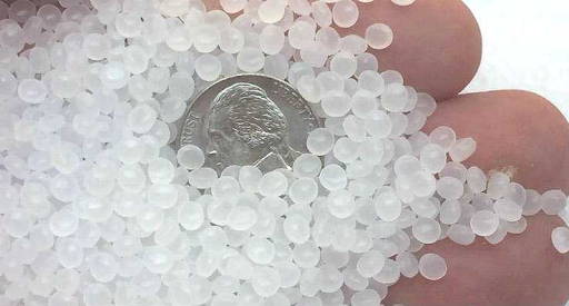 Glass beads used as filling in a weighted blanket compared to a penny - Photo from Weighted Blanket Guides