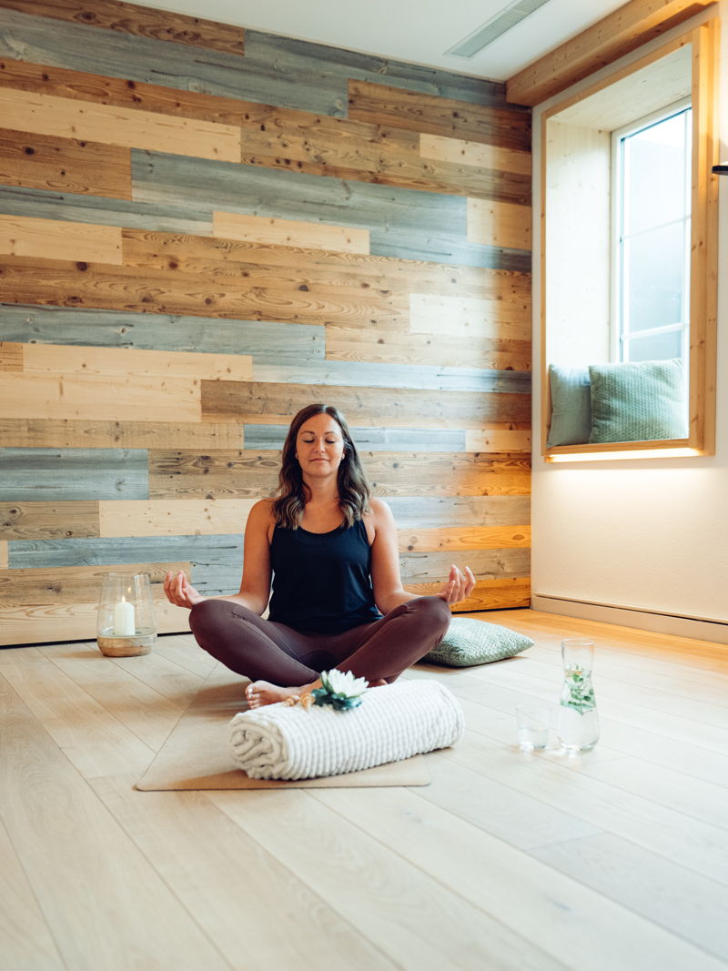 Eine Frau in Sportkleidung meditiert sitzend auf einer Yogamatte.