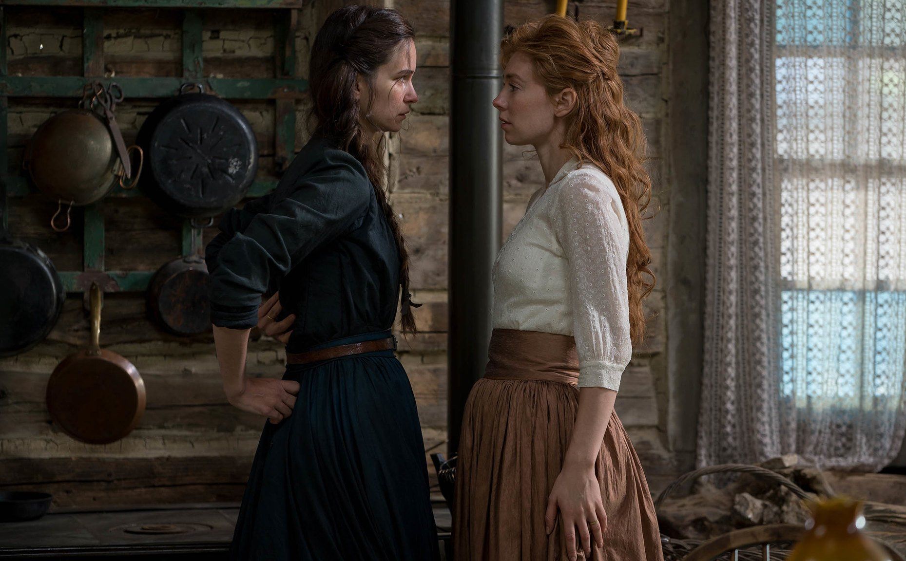 Tallie confronting Abigail inside their cabin. Both have serious looks on their faces.