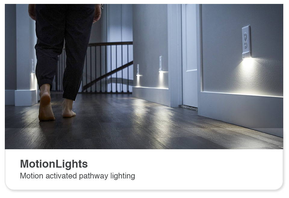 Person walking down hallway at night with multiple motion outlet light covers on wall