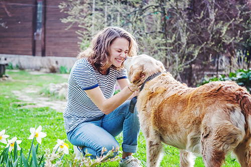 Woman crouching down to happily pet her dog
