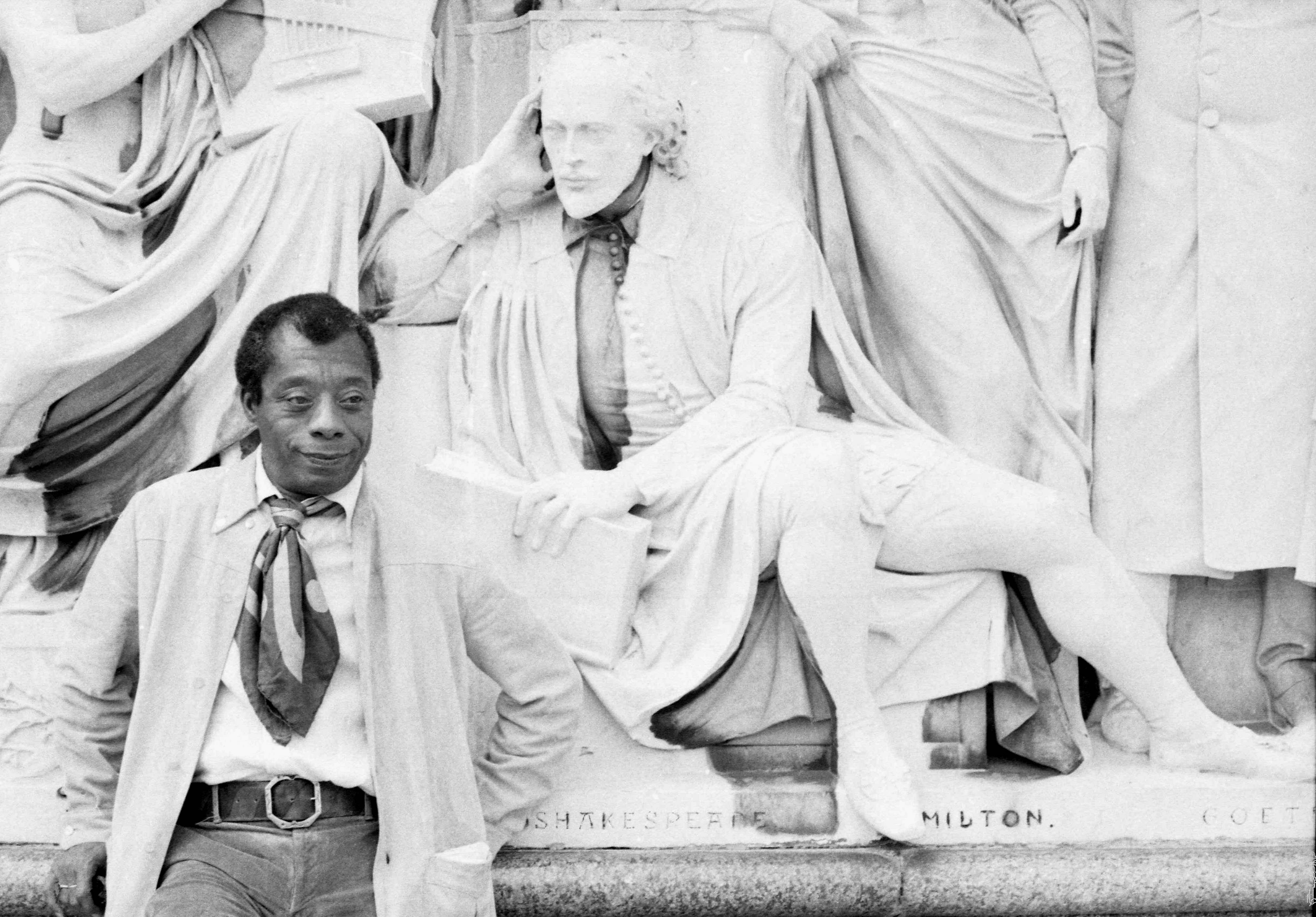 James Baldwin on the Albert Memorial with a statue of Shakespeare, he has his hands behind his back.