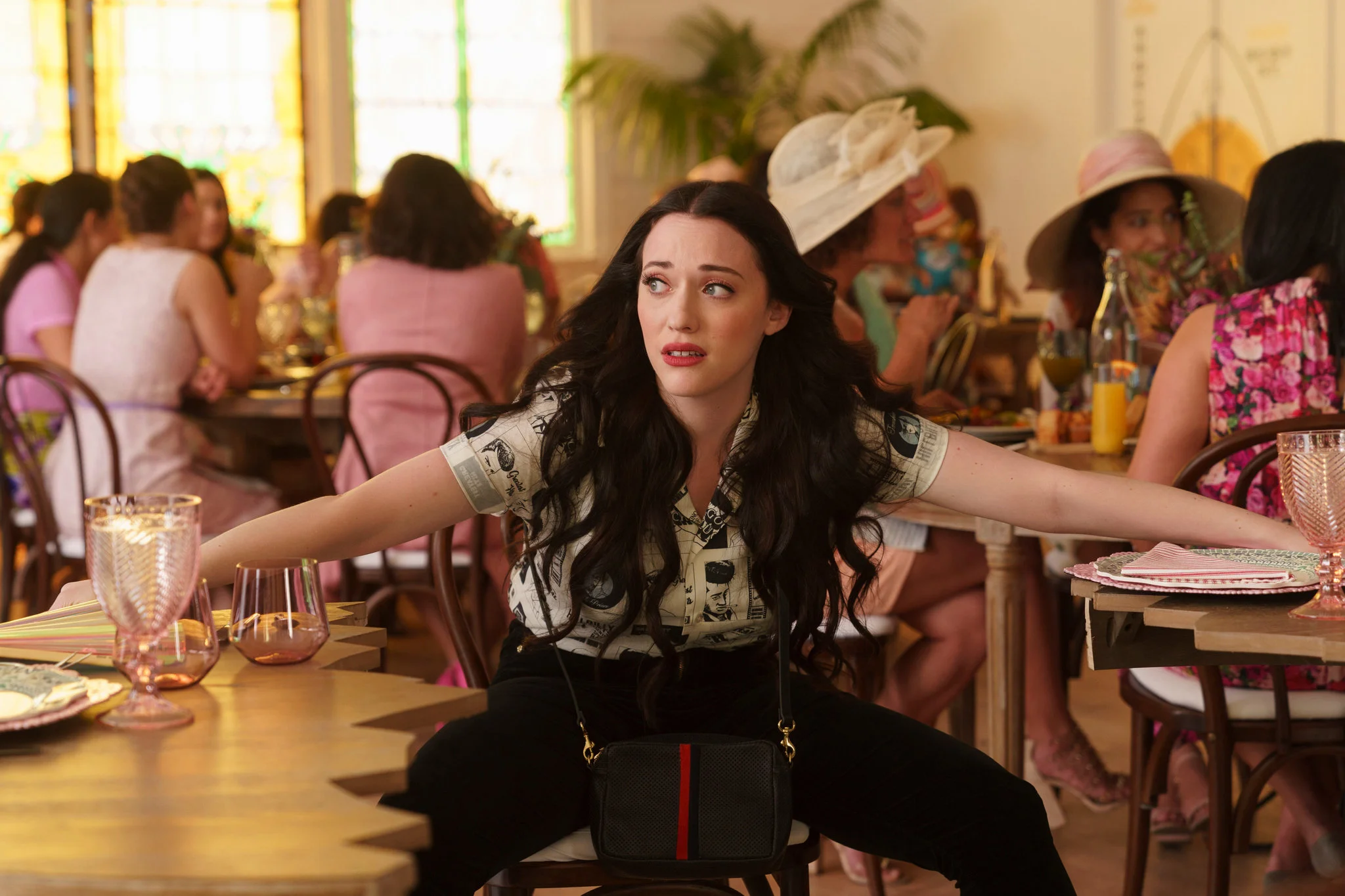 Jules with a worried expression, with her arms spread out over two tables at a restaurant.