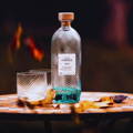 Bouteille de Gin écossais Isle of Harris Gin posée sur une table d'extérieure à côté de deux verres