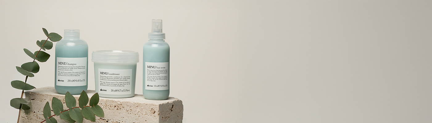 Davines MINU line sitting on a bench with a green plant next to it