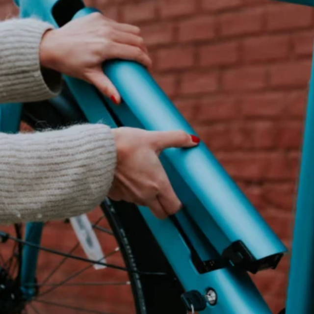 a woman putting a blue electric battery into a blue electric city bike