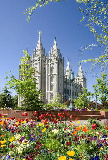 Salt Lake Temple on a sunny day surrounded by colorful flowers.