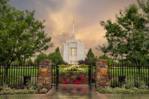 An open gate leading to the Twin FAlls TEmple and it's vibrant flower beds and lawn.
