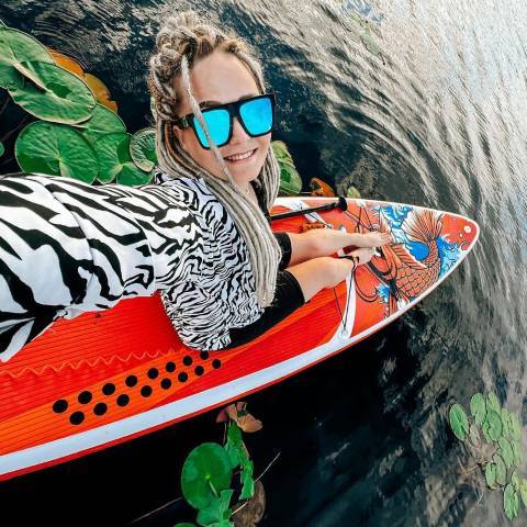 Customer sit in Koi blow up stand up paddle board and smile
