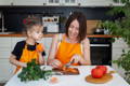 Mother and daughter slicing vegetables on the kitchen table.