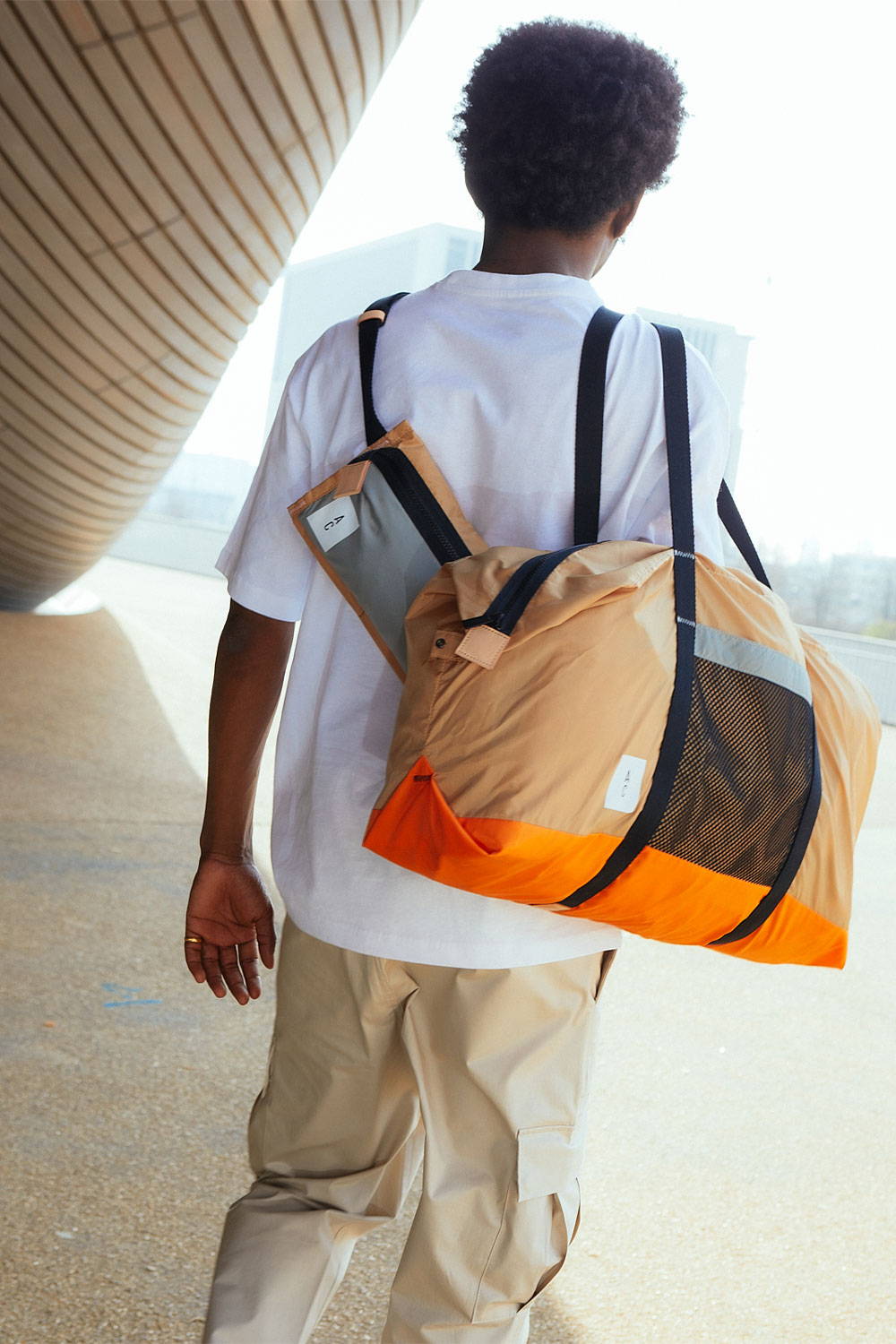 Ally Capellino SS22 Packable Collection Campaign Model Wearing Hoff Holdall and Herbert Crossbody Bag in Beige