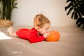 Baby biting a pumpkin while laying on the bed.