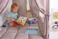 Toddler reading Montessori books independently in a cozy reading corner with soft books and child-sized seating