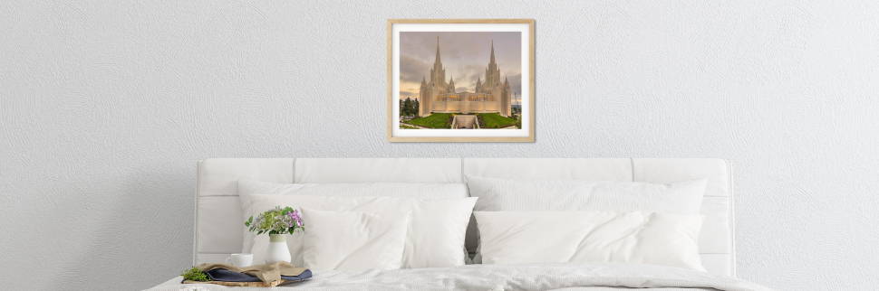 Banner image of a San Diego Temple photo hanging above a white bed.