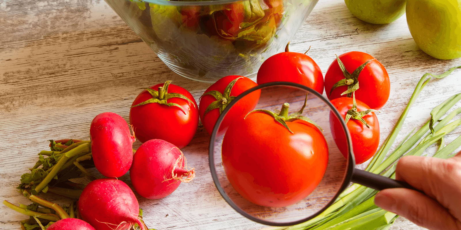 Fresh fruit on counter with a magnifying glass zoomed in on a tomato.