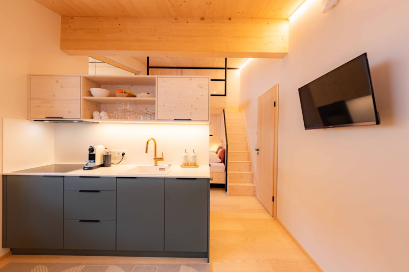 Moderne Küchenzeile mit Kochfeld, Spüle und offenem Wohnraum im Apartment von Hugo & Pepi in Mittelberg.