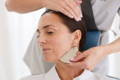 woman performing a gua sha facial massge on a client 