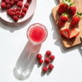 Vegan collagen powder mixed with water in a glass with strawberries and raspberries