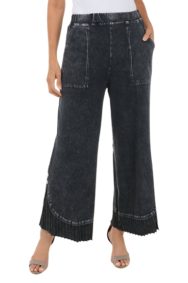 A woman wears a pair of black mineral wash pleated hem pants.