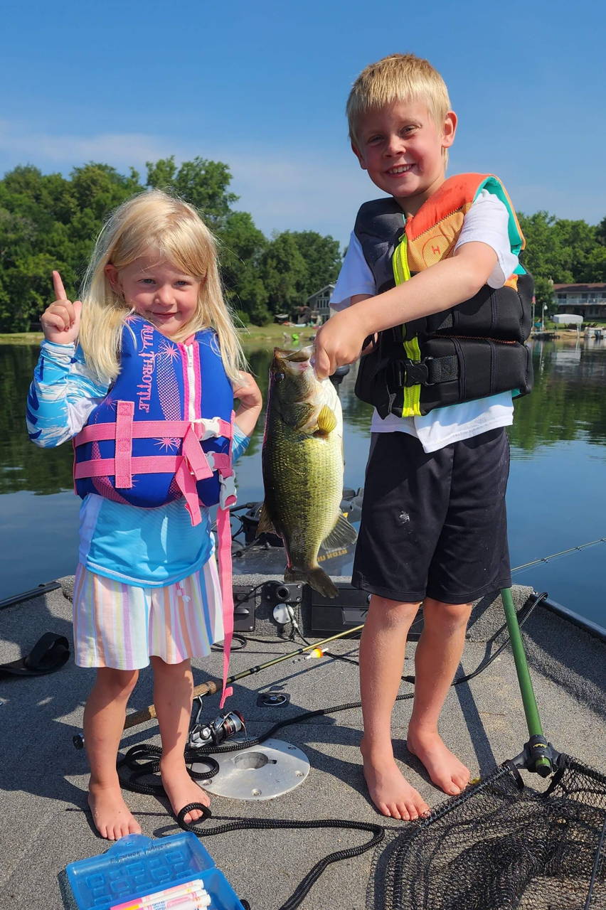 Two children wearing life jackets with their catch on a fishing boat