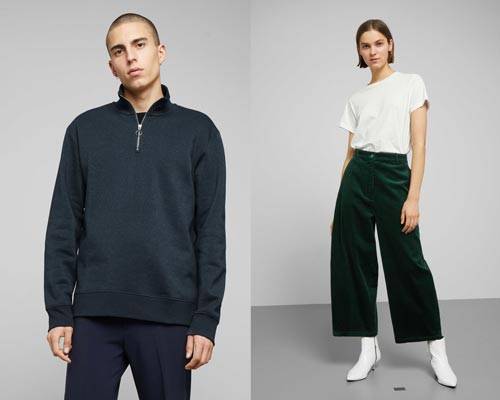 Man wearing dark navy blue quarter zip organic cotton jumper with navy trousers and woman wearing white organic cotton t-shirt tucked into organic cotton green wide leg cords with white heeled ankle boots from sustainable fashion brand Weekday