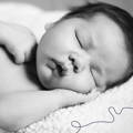 Black and white photo of baby sleeping to the side on hand