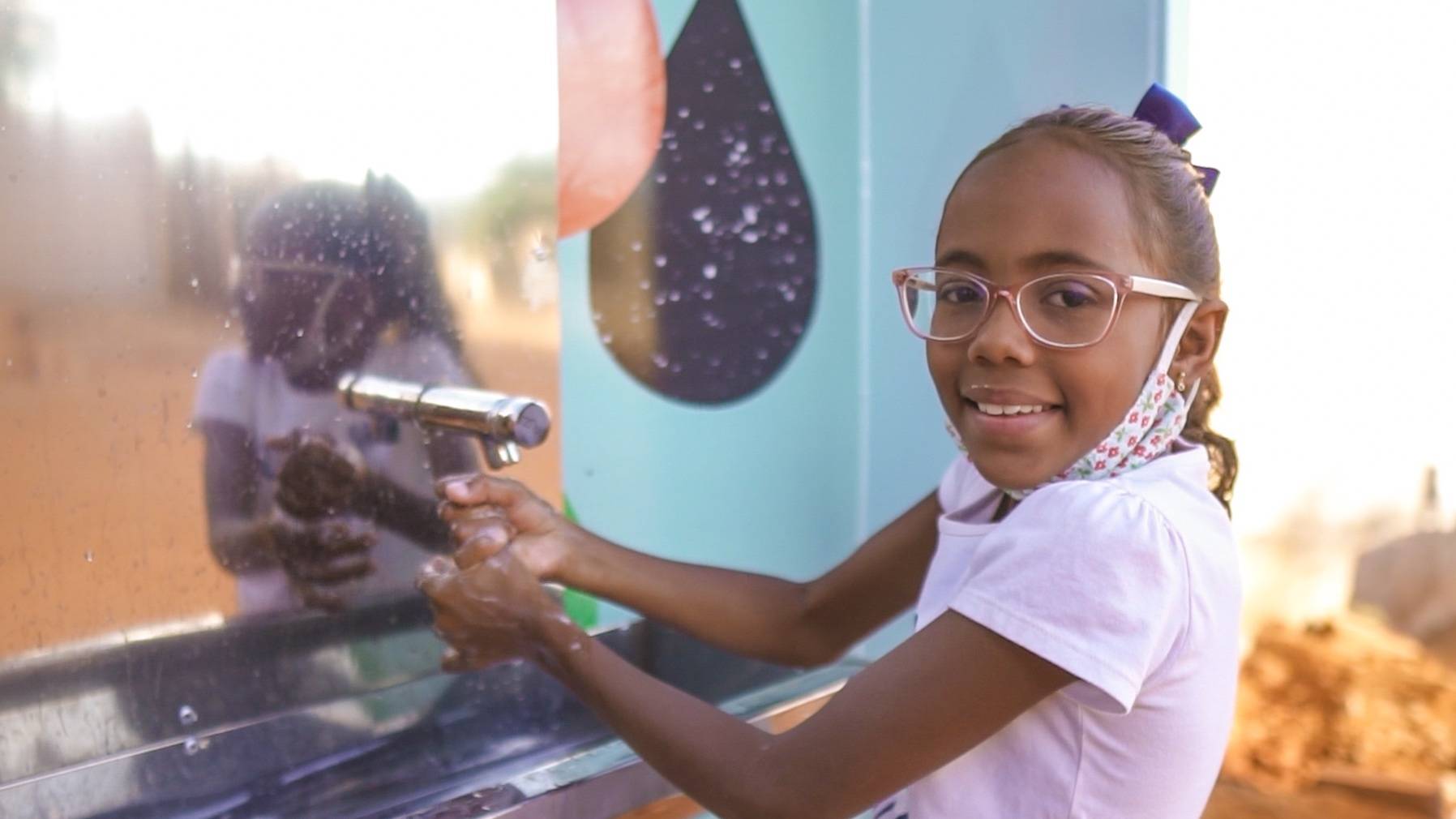 Niña con una de nuestras estaciones de agua en Brasil