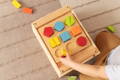 Toddler playing with wooden Montessori shape puzzles.