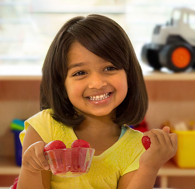 A kid holding bowl of strawberries