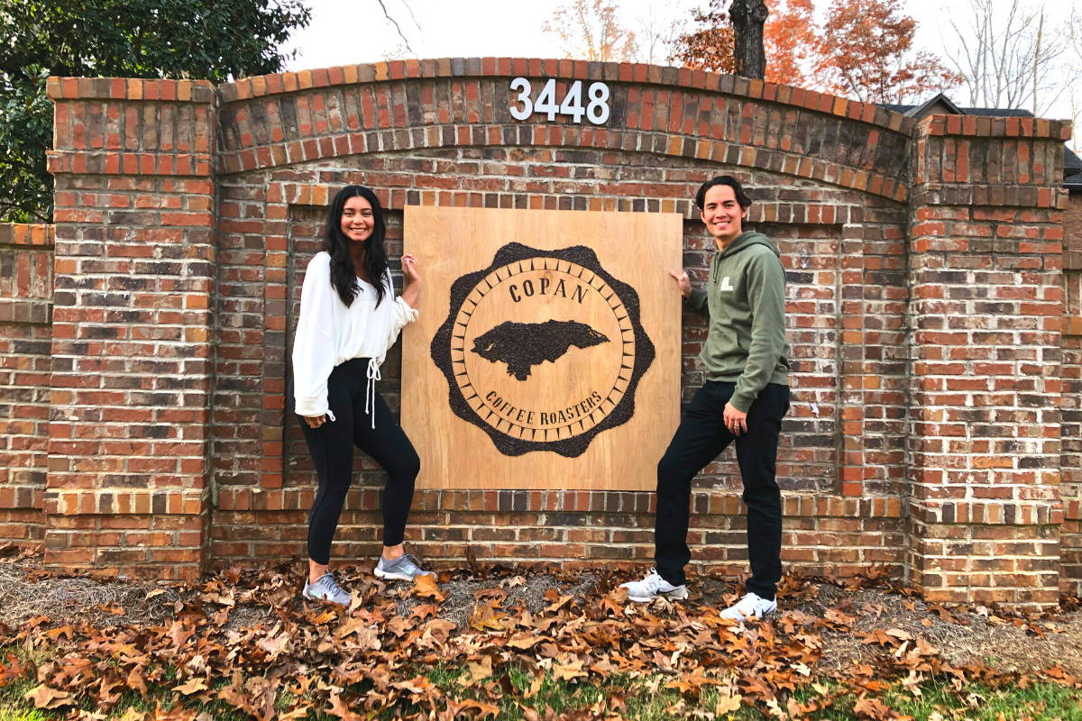 Harry and Leticia standing by a Copan Coffee Roaster sign.