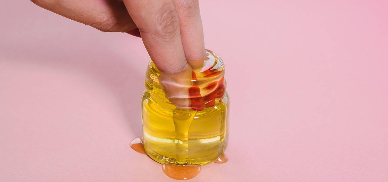 Finger, die in ein Glas Honig eintauchen