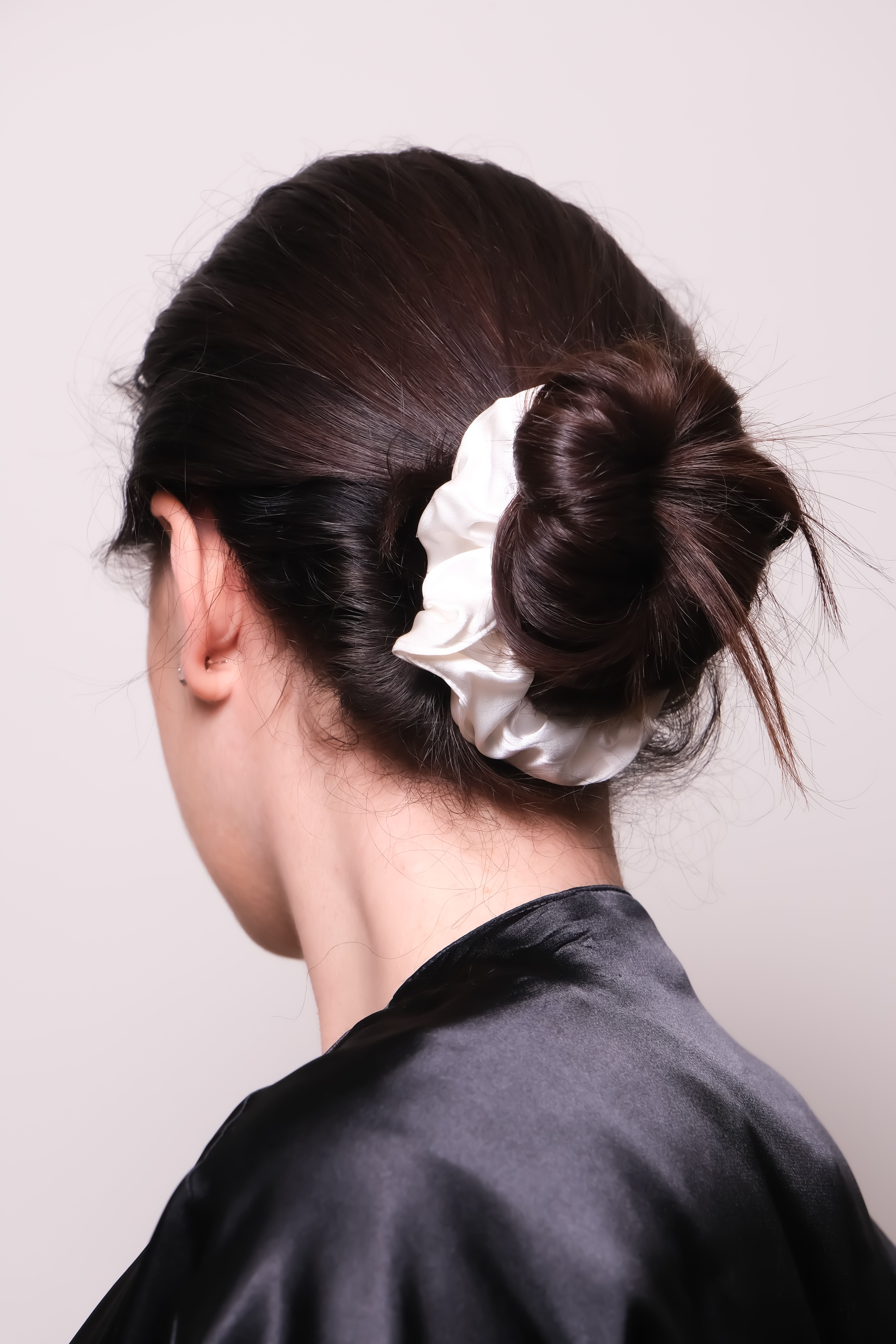 White silk scrunchie worn in a hair bun