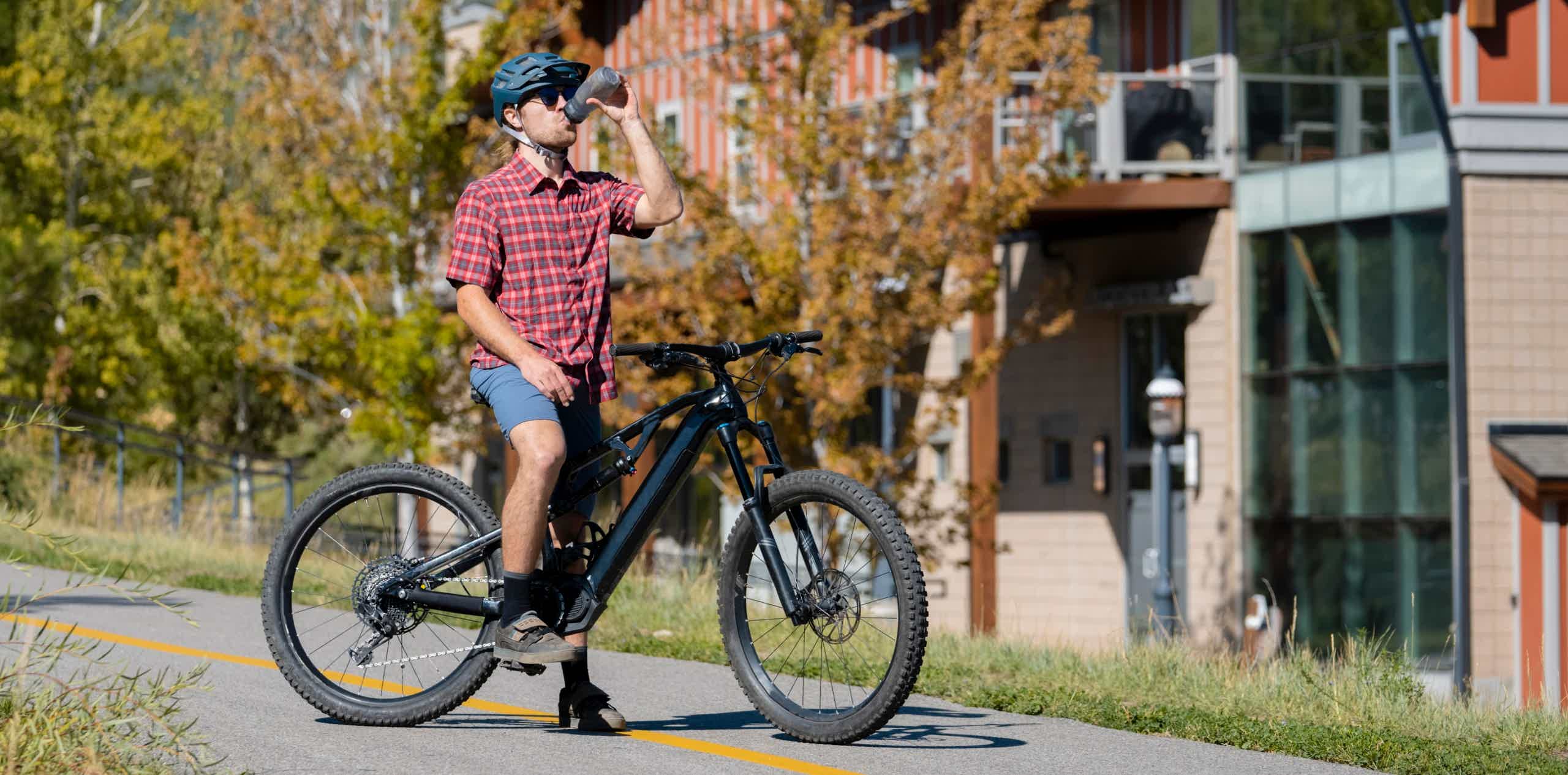 Imagen de recurso de un hombre con su e-bike bebiendo agua.