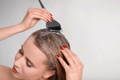 blonde woman applying hair mask on hair with brush
