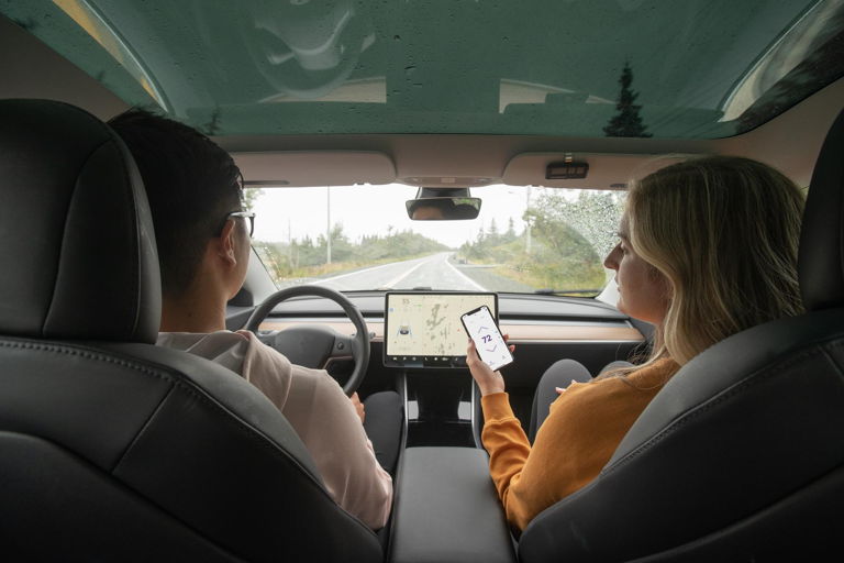 une couple dans une voiture utilisant le contrôle à distance du thermostat intelligent sur le téléphone