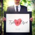 groom holding wedding keepsake art print with red fingerprint heat and script names