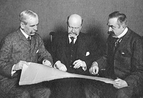 Wead, McKim and White sitting together holding a large paper and looking at it together.