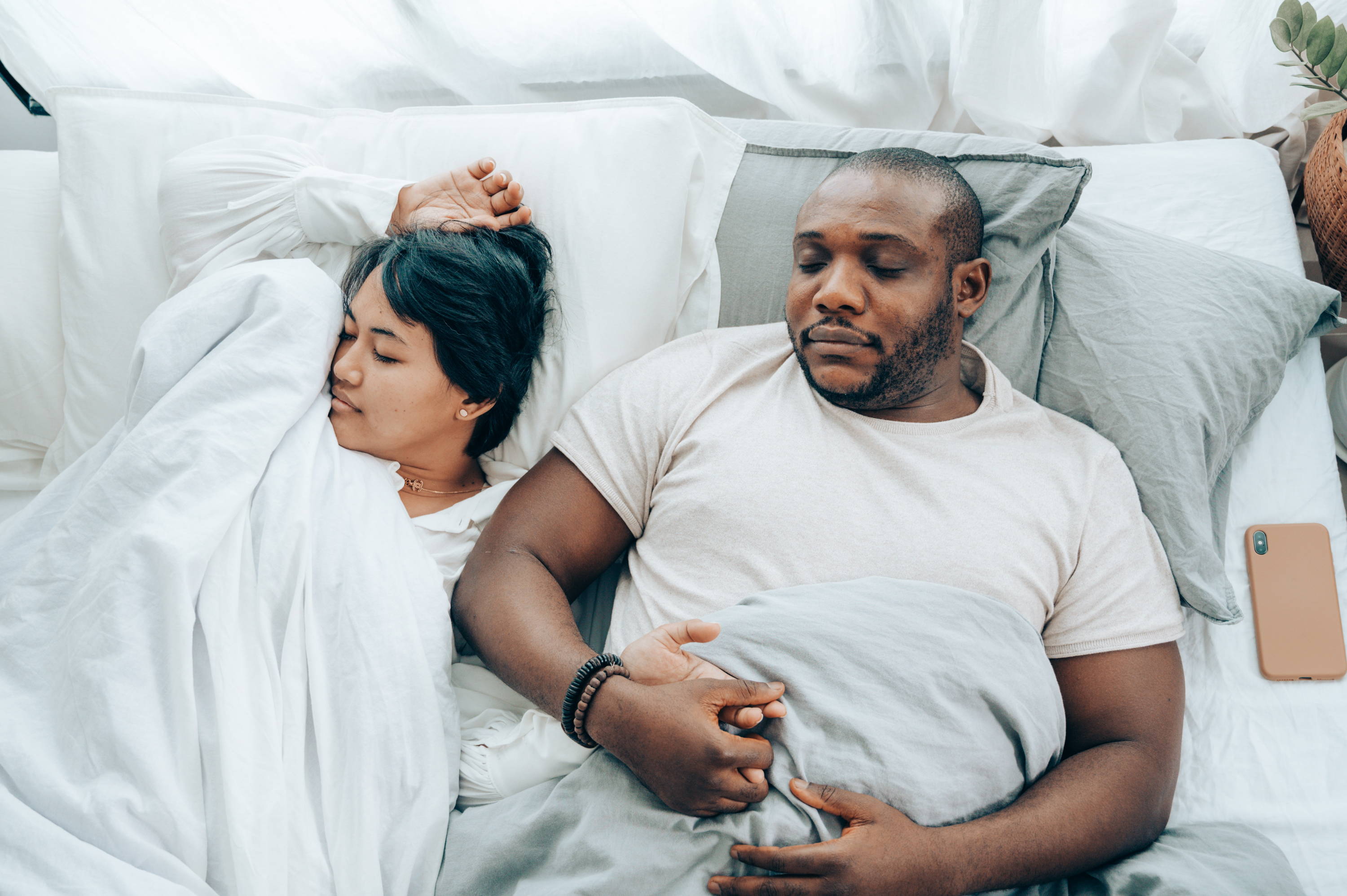 16. Young multiethnic spouses sleeping in bed holding hands - Photo by Ketut Subiyanto from Pexels