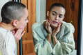 woman looking in the mirror checking her skin condition