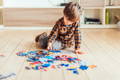 Little boy sitting on the playroom floor and playing with puzzles.