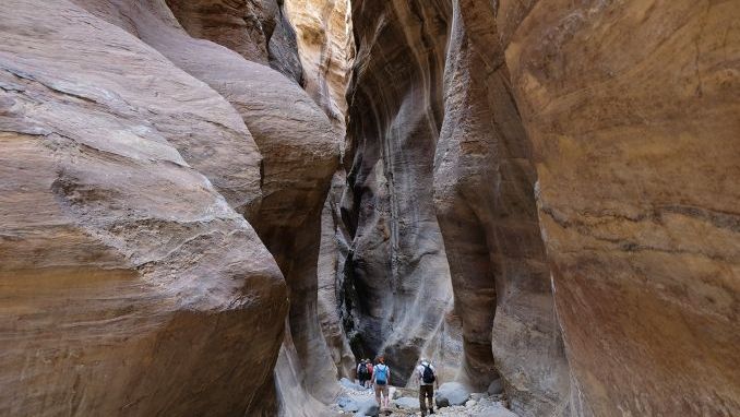 Dana Biosphere Reserve in Jordan. Amazing rocks in Wadi Ghuweir Canyon. Silhouette of hiking people on trail.